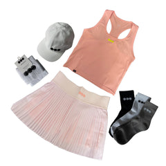 A coordinated activewear set laid out on a white background, including a peach racerback tank top, a light pink pleated tennis skirt, a light gray baseball cap, gray socks on a card, and black and gray socks. The items feature matching three-dot logo details.